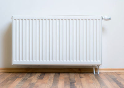 Home radiator heater on the white wall on wooden hardwood floor